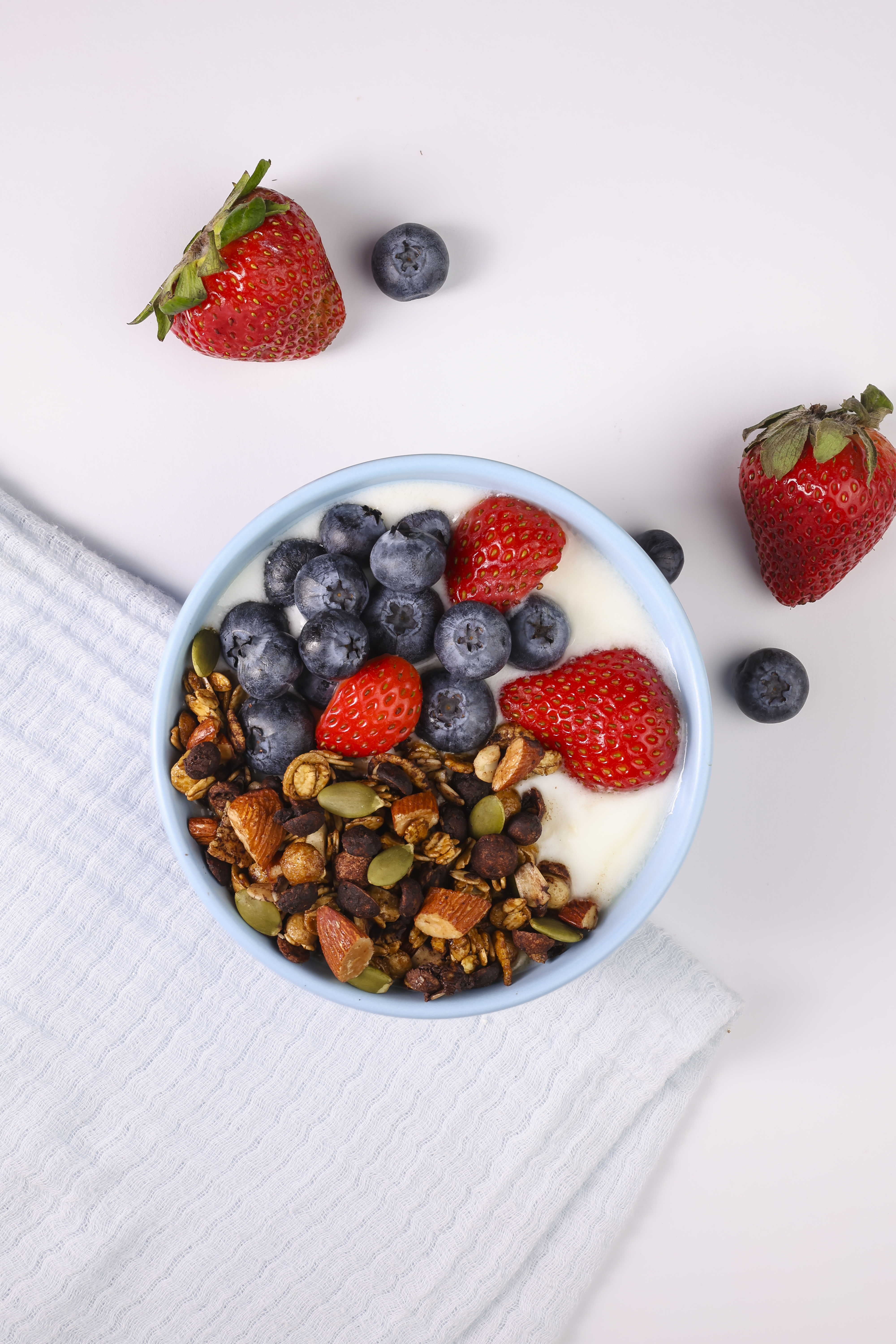 Bowl of healthy snacks with yogurt, blueberries, strawberries, and nuts